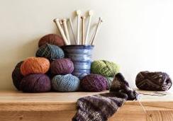balls of yarn and a cup holding knitting needles